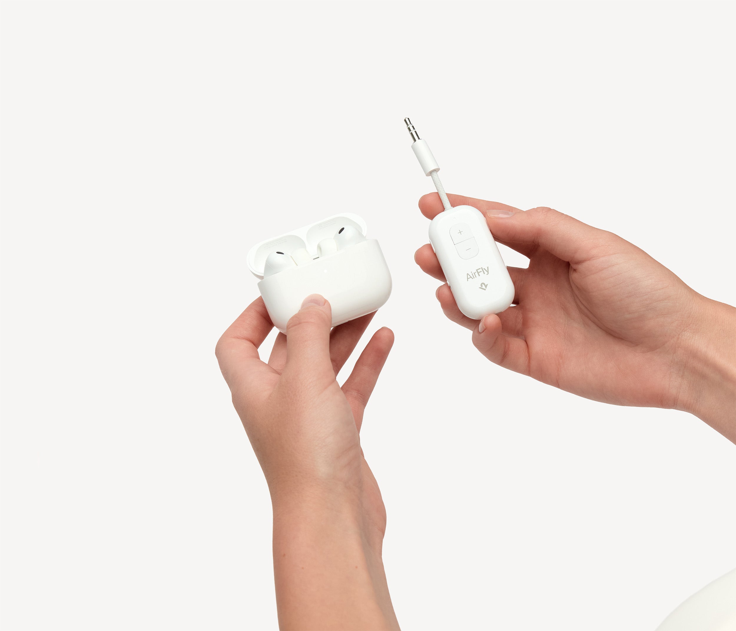 White Twelve South AirFly Pro 2 with plus and minus controls held beside an open AirPods case